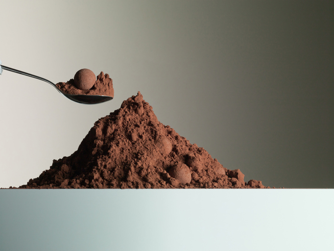 Spoon over heap of cocoa powder
