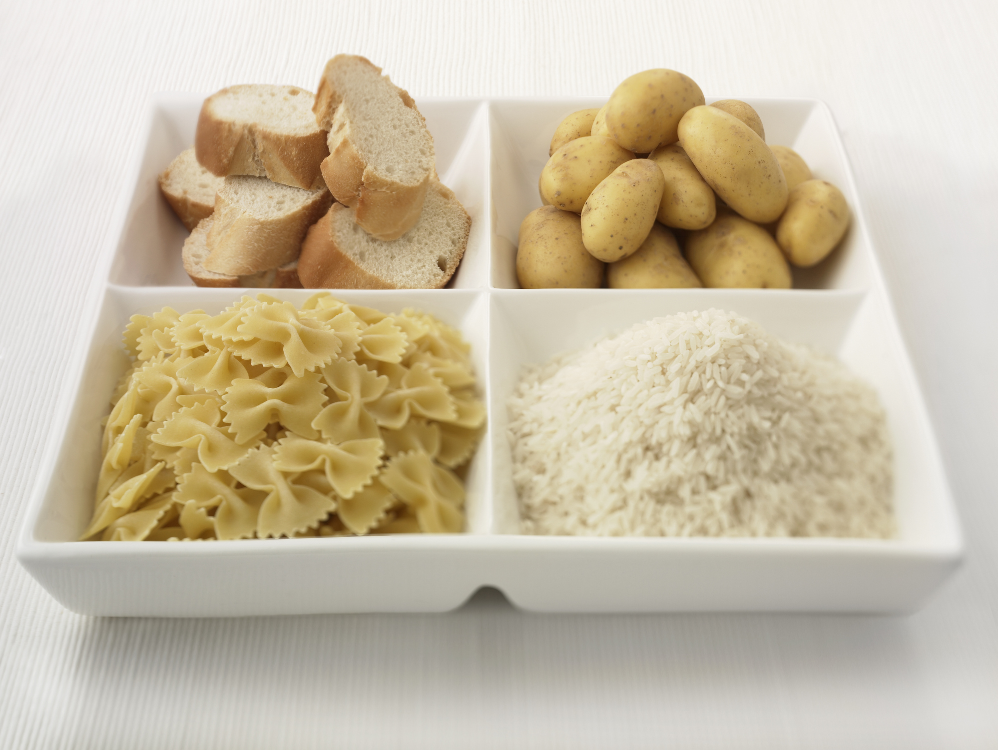 Close up of sectioned plate with bread, potatoes, rice and pasta
