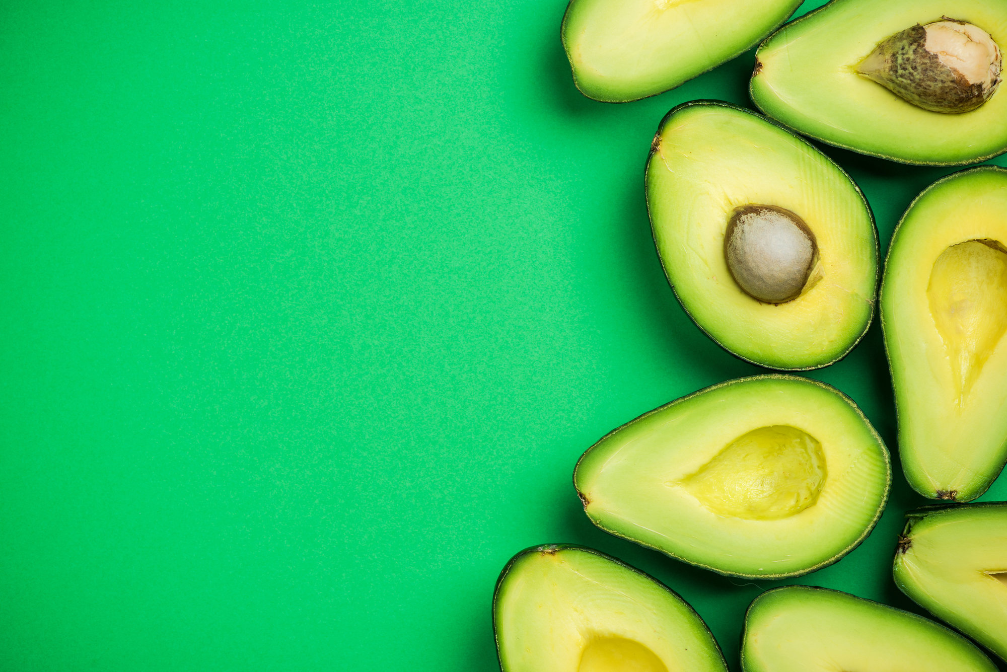 avocado halves on bright green background