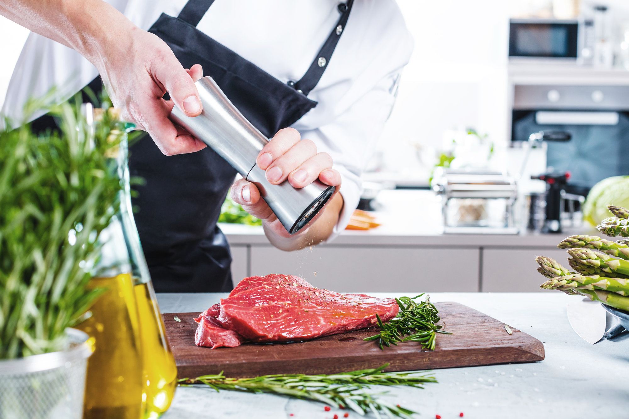 man in kitchen salting raw steak