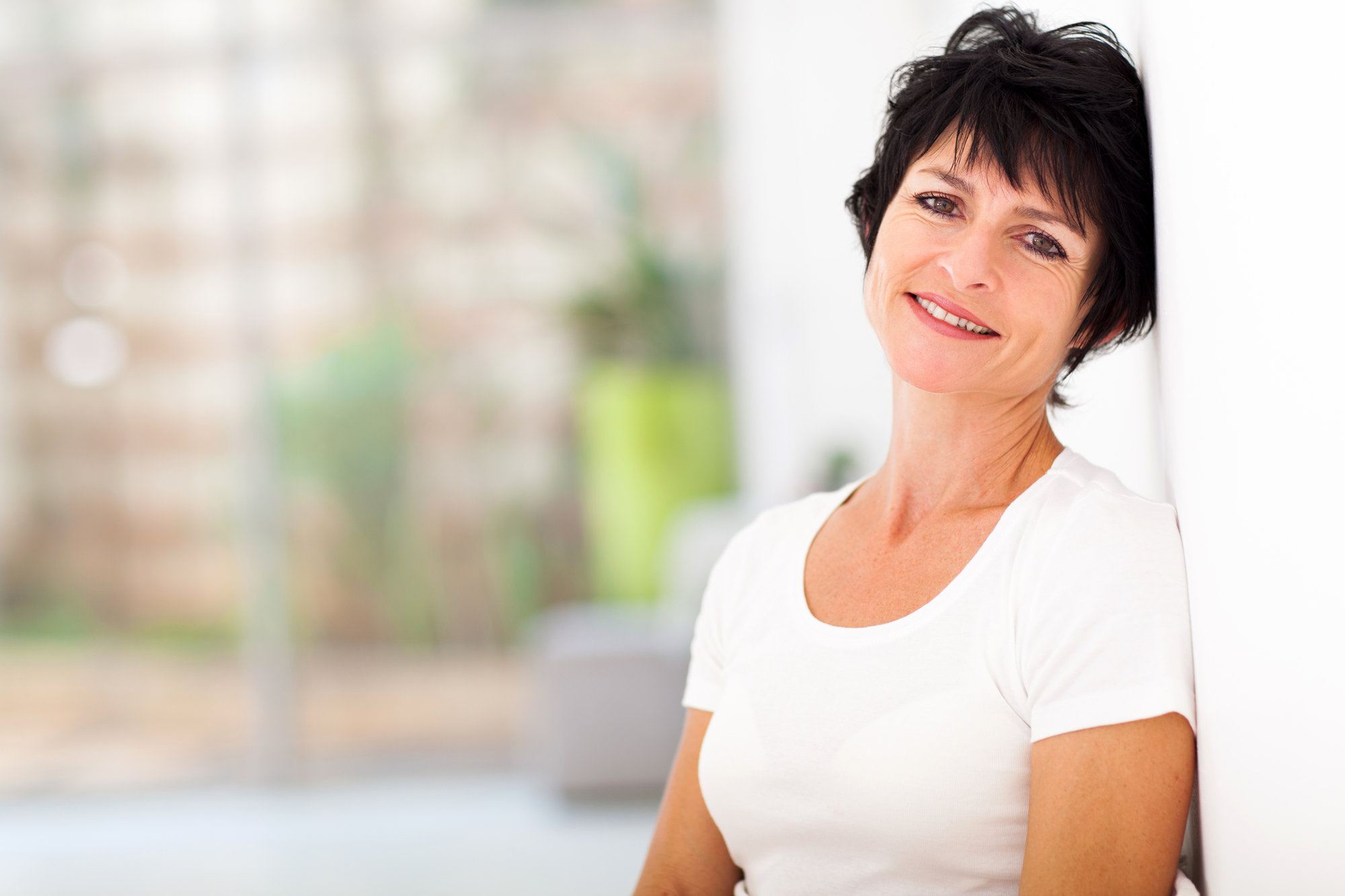 smiling woman with short brown hair wearing a white tshirt