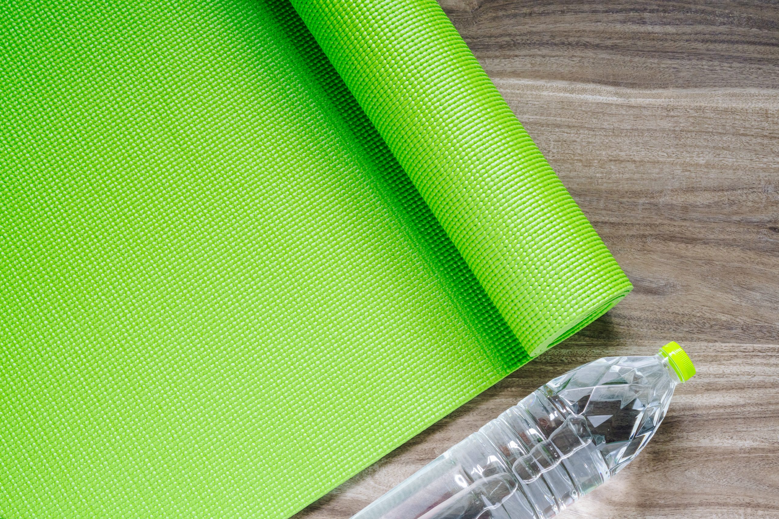 Lime green yoga mat next to water bottle