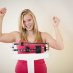Happy blonde woman on weight scale