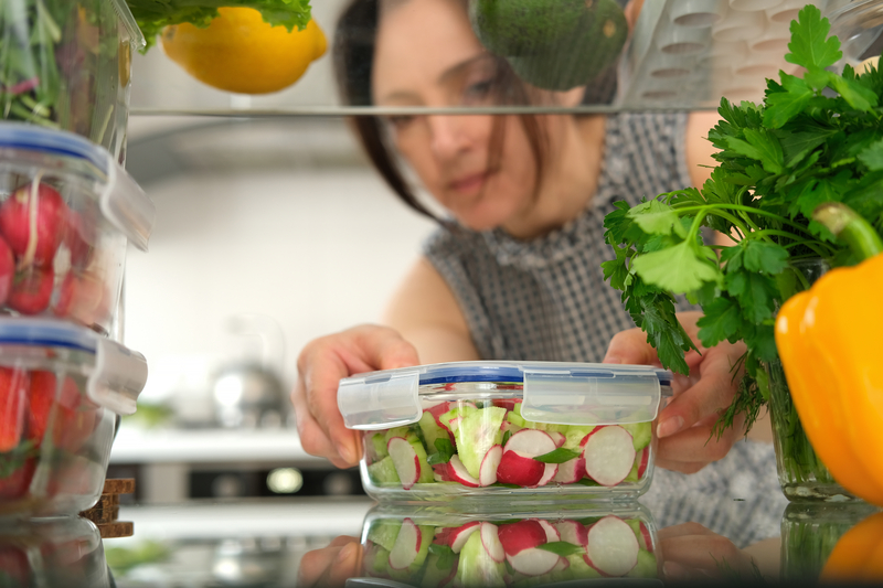 woman reaching for salad in fridge