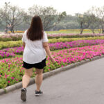 Health care concept overweight woman walking in the park with colorful flower