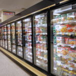 Frozen food cases in a supermarket aisle.