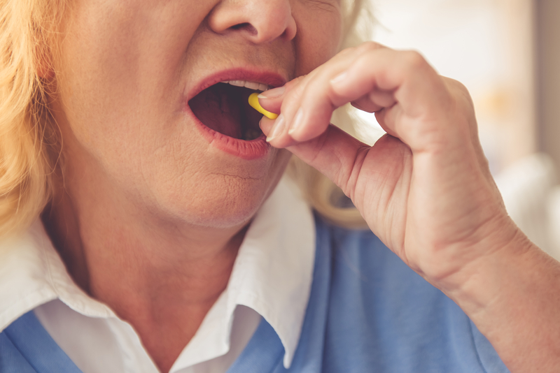 Cropped image of beautiful mature woman taking pill, close-up