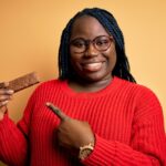 woman with braids eating healthy protein bar very happy