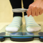 Woman feet on weighing scales looking weight over magnifying