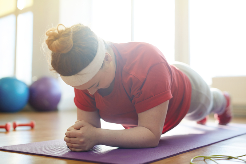 woman working out on yoga mat in sunlit fitness studio: holding plank exercise